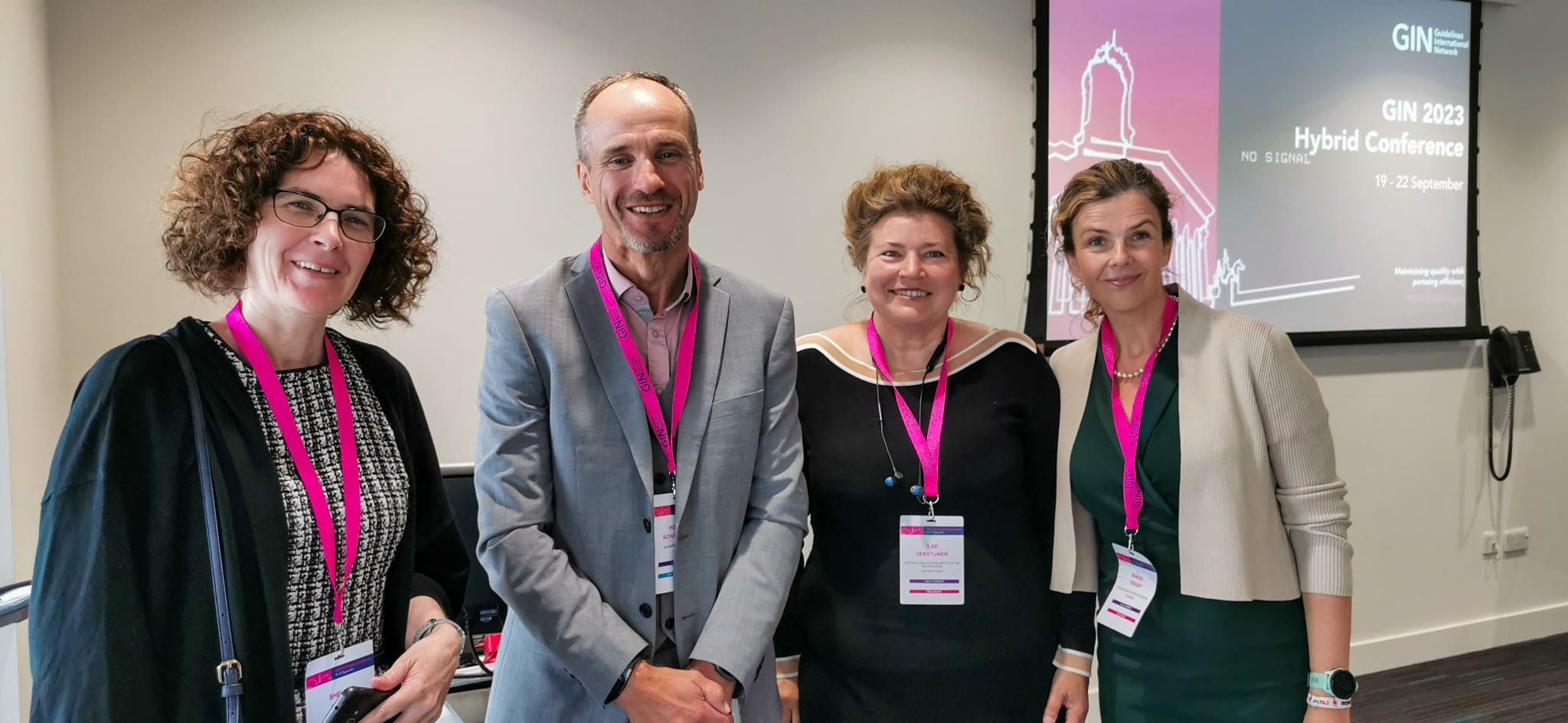 HIQA staff members and Dr Holder Shumann are photographed standing in front of a presentation screen.